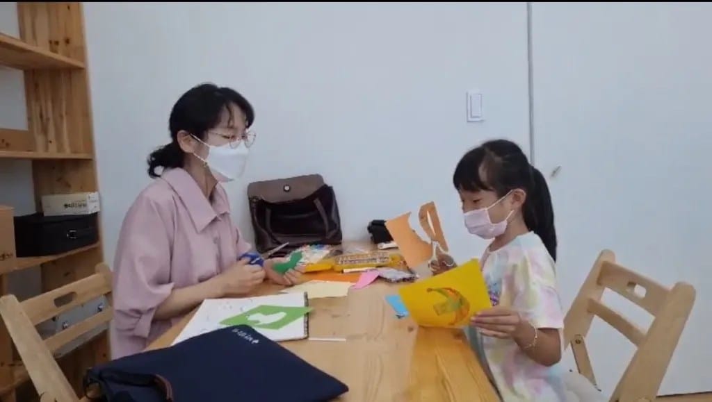 선생님과 종이 만들기 활동을 하는 아이